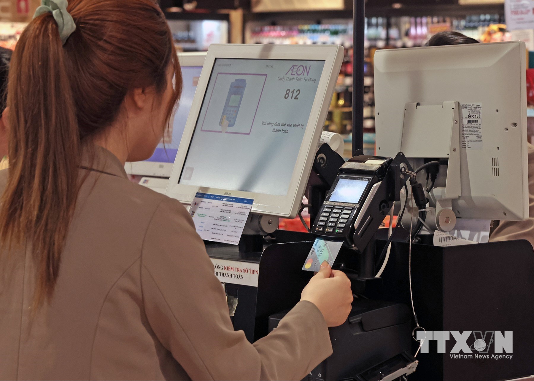Bằng những thao tác đơn giản, tiết kiệm thời gian, người mua và hệ thống các cửa hàng dễ dang kiểm soát được số tiền giao dịch cho mỗi lần chạm. (Ảnh: Trần Việt/TTXVN)